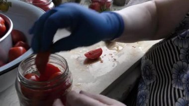 Bir kadın konserve domates hazırlar.