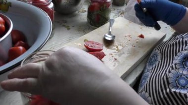 Bir kadın konserve domates hazırlar.