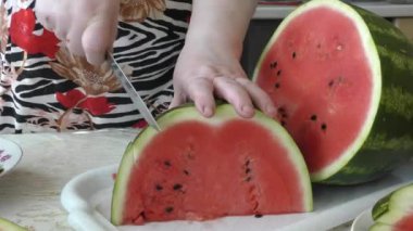 Bir kadın olgun bir karpuzu bıçakla keser.