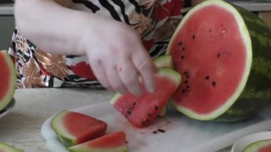 Bir kadın olgun bir karpuzu bıçakla keser.