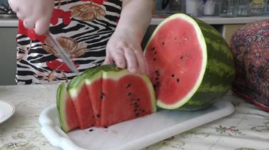 Bir kadın olgun bir karpuzu bıçakla keser.
