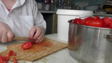 Bir kadın bıçakla domates kesiyor.