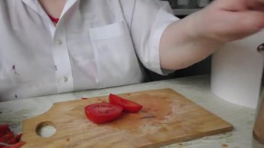 Bir kadın bıçakla domates kesiyor.
