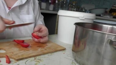 Bir kadın bıçakla domates kesiyor.