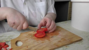 Bir kadın bıçakla domates kesiyor.