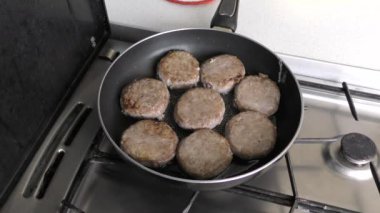 Aşçı kızartma tavasında et pirzolası pişirir.