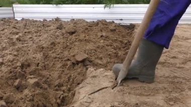 Bir adam kürekle toprağı kazıyor.