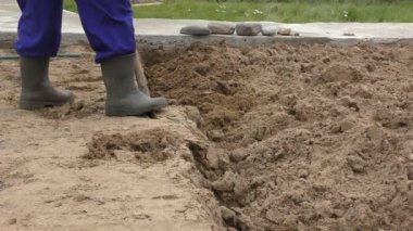 Bir adam kürekle toprağı kazıyor.