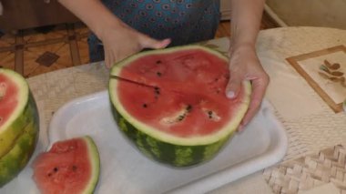 Bir kadın olgun bir karpuzu bıçakla keser.