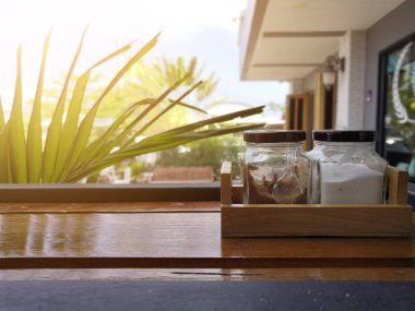 Kahve dükkanında ahşap masada küçük bir cam şişe beyaz şeker ve kahverengi şeker.