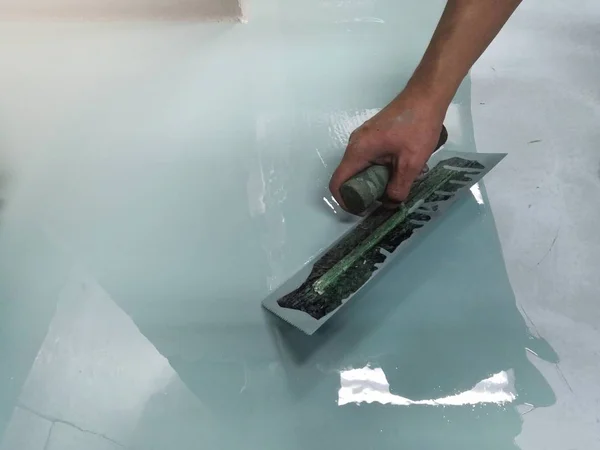 建設作業員は 自己平準化エポキシを使用して床を塗装しています セルフレベリングエポキシ セメント床の混合物との平準化 — ストック写真