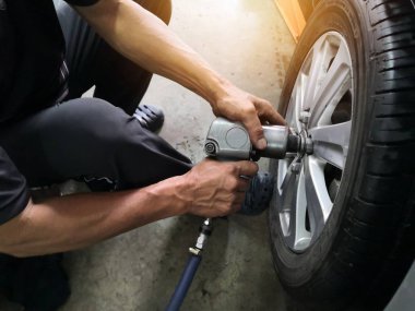 Sızdıran lastik araba tekerlekleri onarmak için araba tamircisi çıkarma. Mekanik bir araç üzerinde bir asansör cıvata gevşetmek için bir elektrikli matkap kullanarak bir araba lastik değiştirme .servis veya değiştirme kavramı.