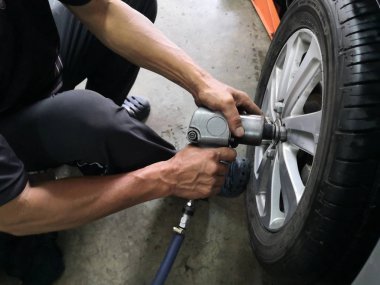 Sızdıran lastik araba tekerlekleri onarmak için araba tamircisi çıkarma. Mekanik bir araç üzerinde bir asansör cıvata gevşetmek için bir elektrikli matkap kullanarak bir araba lastik değiştirme .servis veya değiştirme kavramı.