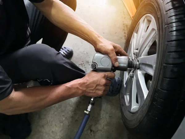 Sızdıran lastik araba tekerlekleri onarmak için araba tamircisi çıkarma. Mekanik bir araç üzerinde bir asansör cıvata gevşetmek için bir elektrikli matkap kullanarak bir araba lastik değiştirme .servis veya değiştirme kavramı.