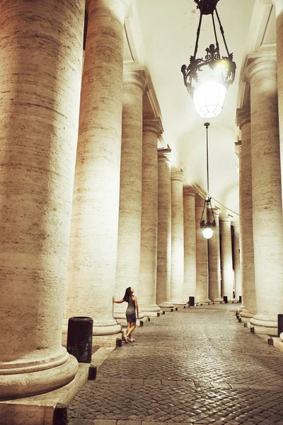 Toeristische vrouw die 's nachts door de zuilen van het Vaticaan loopt — Stockfoto