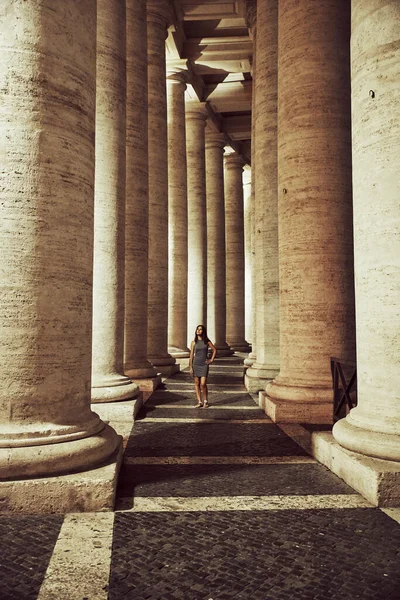 Tourist woman walking at night through the columns of the Vatican — Stock Photo, Image