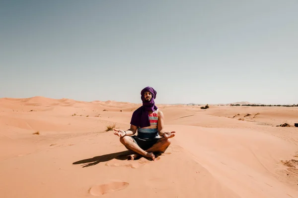 Man in turban meditating on a dune in the desert — Stockfoto