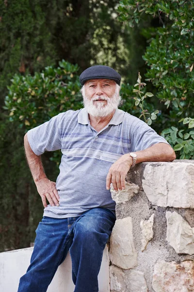 Yeşil arka planda bere takan şık, yaşlı bir adamın portresi.