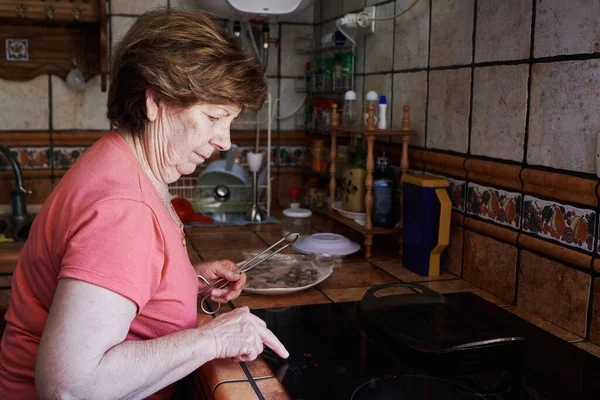Yaşlı bir kadın cam seramik yakıyor. Yaşlılar konsepti