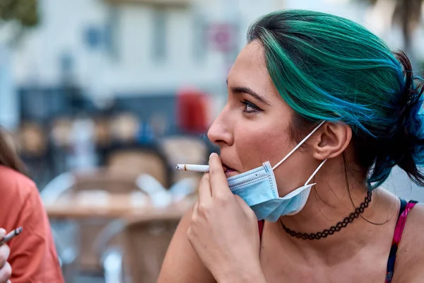 a young girl smoking a cigarette with a mask. Concept pandemic