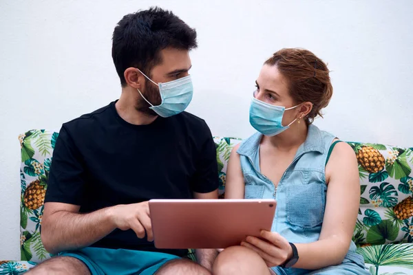 Cerrahi maskeli bir çift tablet kullanarak tatil yeri seçiyor. Tatil kavramı