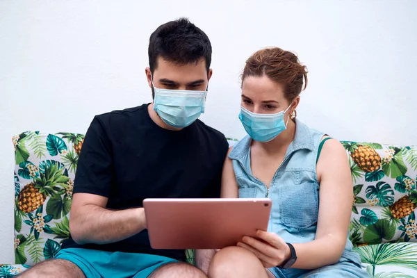 Cerrahi maskeli bir çift tablet kullanıyor. Sorumluluğu kabul et
