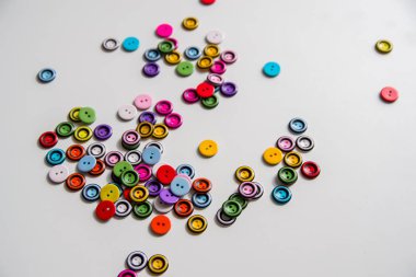 düğmeleri beyaz bir arka plan üzerinde dağınık. Düğmeler renkli, yuvarlak, iki delikli plastik.