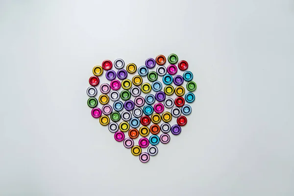 heart of colorful round buttons on light background