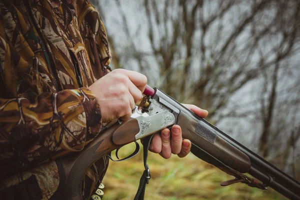 Hunter silahı dolduruyor. Erkek eller fişeği tutar..