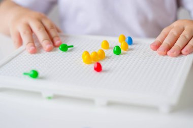 Küçük renkli detaylar mozaiğindeki oyun alanı. Bebek kalemleri mozaik oyunu aldı.