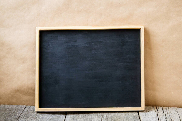 Chalk board on a background of craft paper and on an old wooden table.