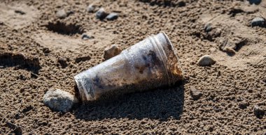 Plastik cam sahilde yatar ve denizi, nehri kirletir. Çöp, çöp, çöp, çevre kirliliği. Plastik denizlerin ve okyanusların kirlilik kontrolü kavramı.