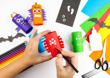 Cadılar Bayramı süsü. DIY ve çocukların yaratıcılık konsepti. Adım adım: Renkli tuvalet kağıdı rulosundan canavar yap. 9.adım yapıştırıcı ya da ağız ve kaşları boya.