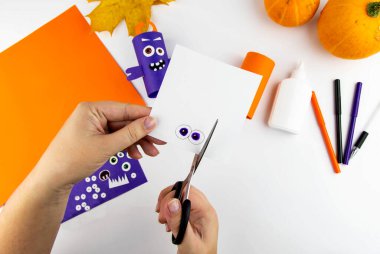 Cadılar Bayramı süsü. DIY ve çocukların yaratıcılık konsepti. Adım adım: Turuncu ve mor kağıtlardan oluşan tuvalet kağıdından canavar yap. 8. Adım Gözleri oyar.