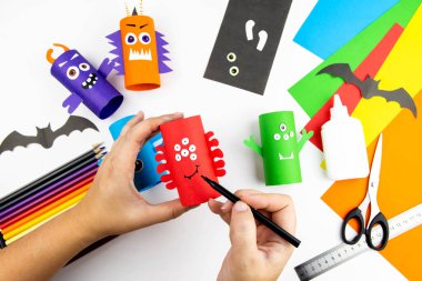 Cadılar Bayramı süsü. DIY ve çocukların yaratıcılık konsepti. Adım adım: Renkli tuvalet kağıdı rulosundan canavar yap. 9.adım yapıştırıcı ya da ağız ve kaşları boya.