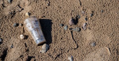 Plastik cam sahilde yatar ve denizi, nehri kirletir. Çöp, çöp, çöp, çevre kirliliği. Plastik denizlerin ve okyanusların kirlilik kontrolü kavramı.