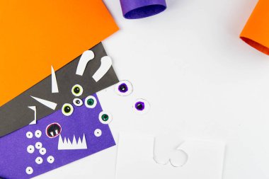Cadılar Bayramı süsü. DIY ve çocukların yaratıcılık konsepti. Adım adım: Turuncu ve mor kağıtlardan oluşan tuvalet kağıdından canavar yap. Dokuzuncu adım, gözlerini oymak..