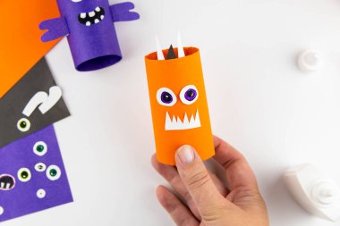 Cadılar Bayramı süsü. DIY ve çocukların yaratıcılık konsepti. Adım adım: Turuncu ve mor kağıtlardan oluşan tuvalet kağıdından canavar yap. 12. adım boynuz, kulak, boya.