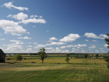 Mavi gökyüzü, güzel bulutlar, renkli çiftlik alanları, ağaçlar ve ahır. Pastoral, güzel manzara arka plan. Kopyalama alanı.