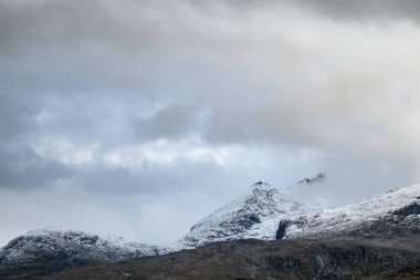 Dağlar beyaz kar tepeleri ve kayalarla, yüksek zirveler Norveç 'te seyahat, Tindevegen' de destansı bulutlar