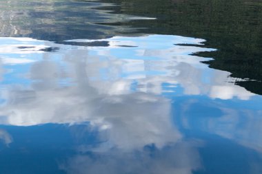 Mavi gökyüzü ve destansı güzel bulutlar Norveç fiyortlarının suyunda yansıyor. Doğal şablon arka planı