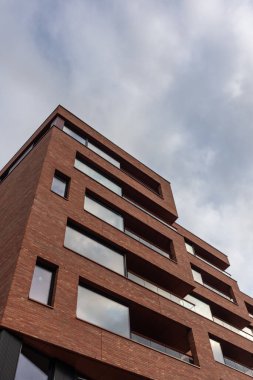 Düşük açılı güzel kırmızı tuğlalar, geniş pencereli modern bina ve gri gökyüzü. Norveç, Oslo 'da yeni bölge mimarisi