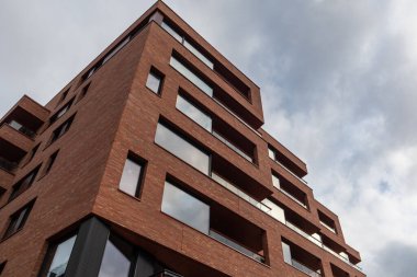 Düşük açılı güzel kırmızı tuğlalar, geniş pencereli modern bina ve gri gökyüzü. Norveç, Oslo 'da yeni bölge mimarisi