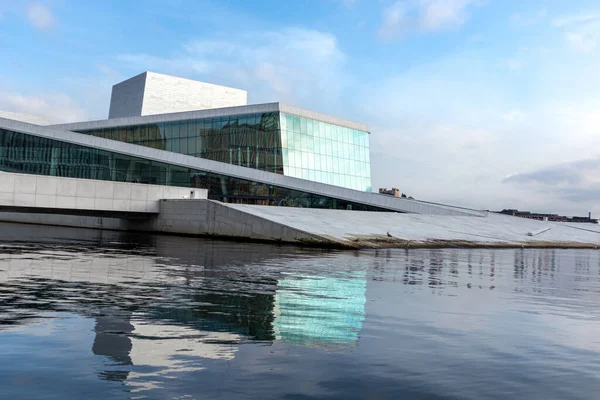 Norveç 'teki Oslo Opera Binası' nda insan yok. Binanın modern mimarisi beyaz granit ve su yansımaları ile parlak mavi gökyüzü manzaralı bulutlar
