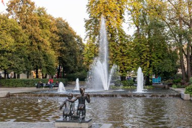 Oslo, Norveç - 10 Eylül 2019: Şehir merkezindeki fıskiyenin yanında çocuk heykeli. Gün batımı altın ışık yaz günü