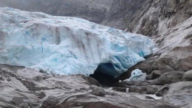 Jostedalsbreen Ulusal Parkı 'ndaki Nigardsbreen' e bulutlu bir gezi. Norveç dağlarının manzarası mavi buz, kaya, buzullar, kar. İklim değişikliği, eriyen buzullar