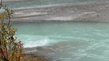 Sonbahar dağları göl mavisi, gök mavisi nehir, sarı turuncu yapraklar ve kayalar ile yakın görüş. Bulutlu bir gün Norveç 'te vahşi doğa yürüyüşü