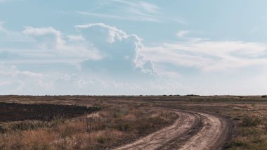 Vahşi sonbahar bozkırlarındaki toprak yol mavi muhteşem bulutlar içinde ufka doğru ilerliyor. Mavi bulutlu alanlarda sürüş