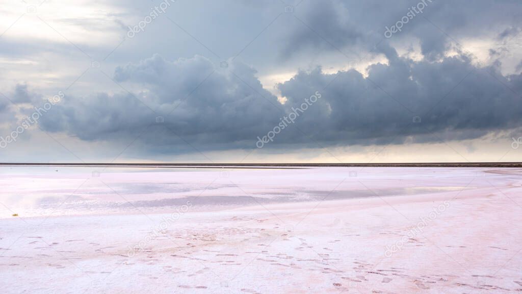 Salt pink lake surface under gray purple high layered epic clouds on sky. Dramatic natural skyline on spa healthcare natural resort