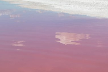 Pembe tuz gölü yüzeyi, ayna bulutlarının yansımasıyla yakın plan. Spa gezisi eğlencesi